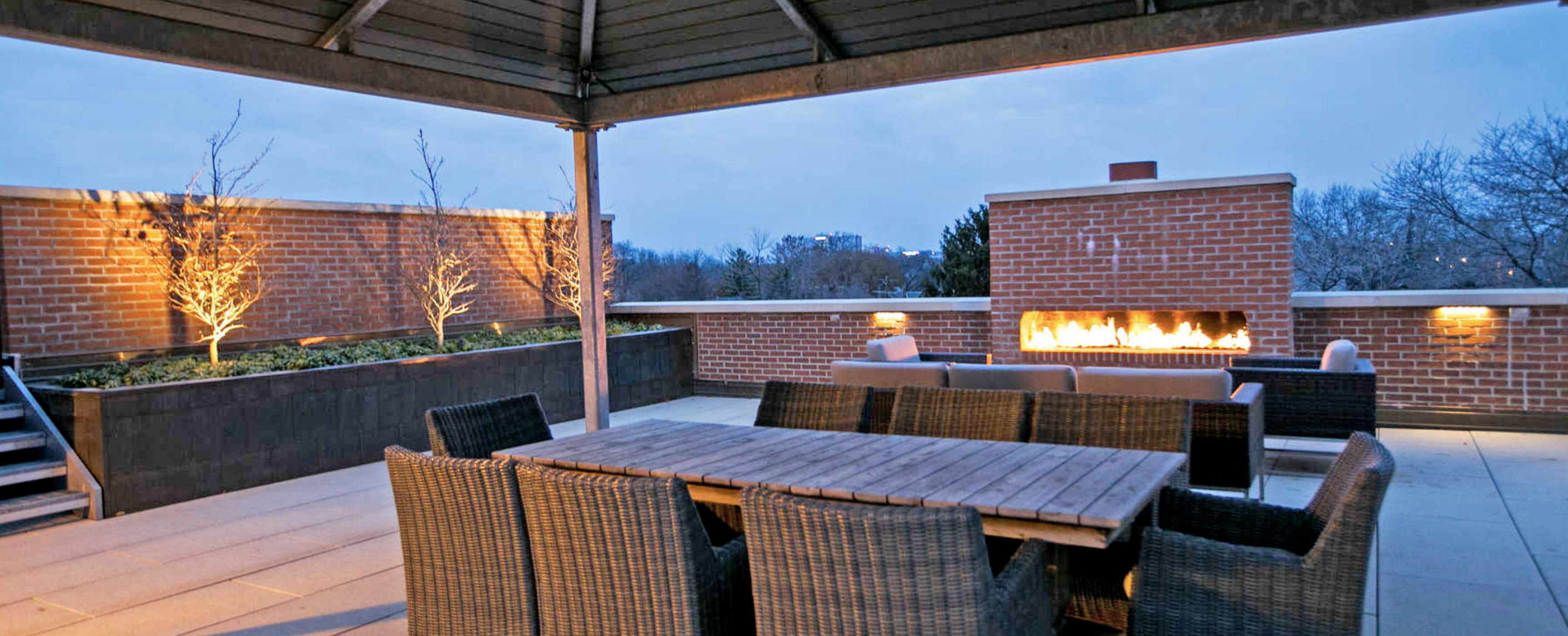 A patio with a fire pit and wicker furniture.