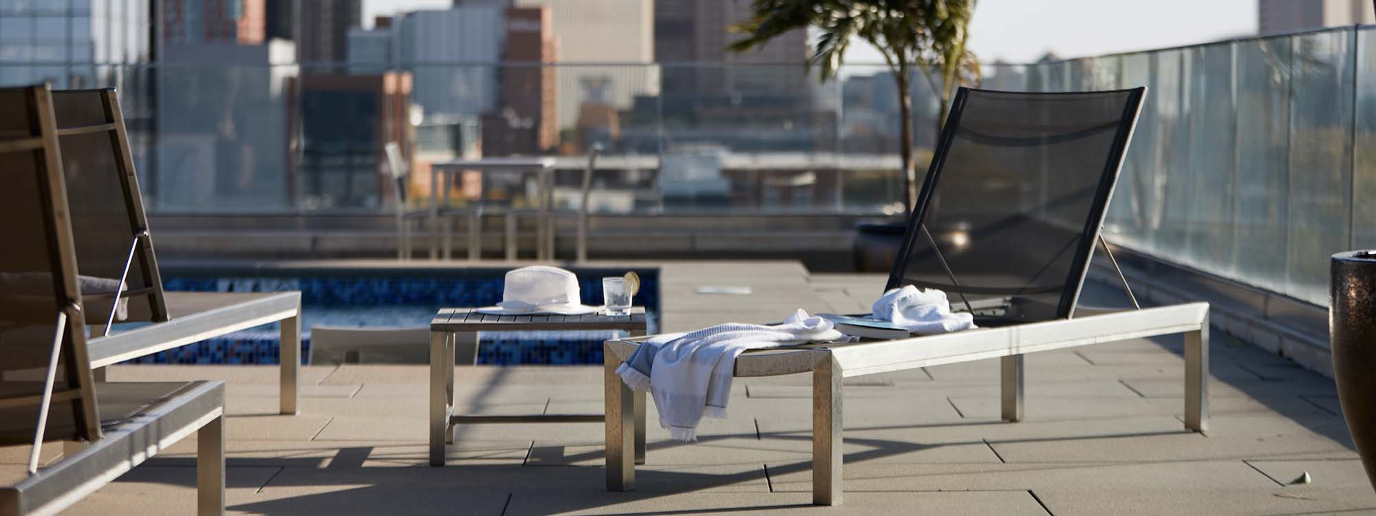 Two lounge chairs on a rooftop with a view of the city.