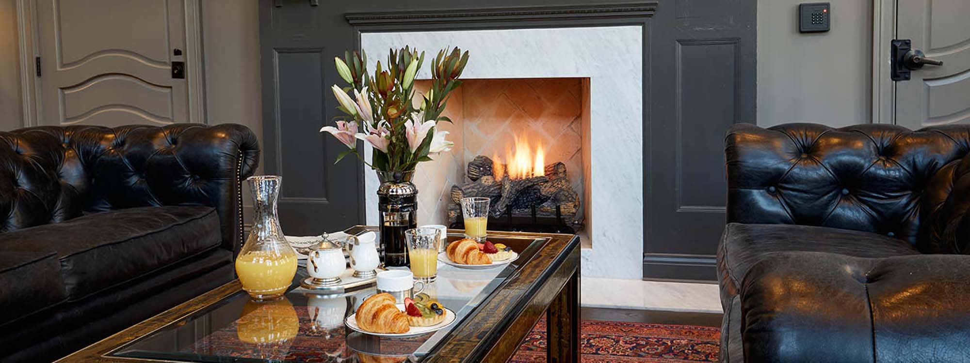 A living room with black leather furniture and a fireplace.