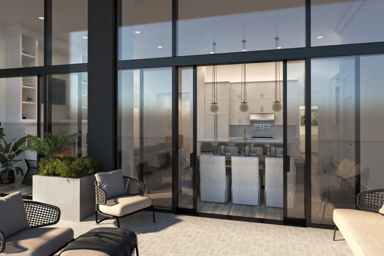 Outdoor seating area with a view of a modern indoor kitchen through large glass windows, featuring pendant lights, bar stools, and potted plants.